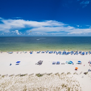 Gaze at the vibrant beach scene below, filled with colorful umbrellas and sunbathers enjoying the gentle waves