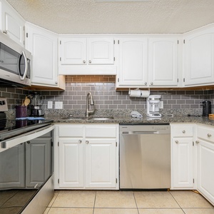 The kitchen features white cabinetry, granite countertops, and stainless appliances, creating a functional and stylish space