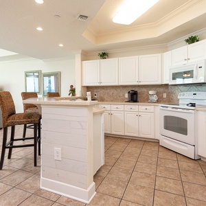 Prepare meals in this kitchen with sleek cabinetry, white appliances, and spacious countertops