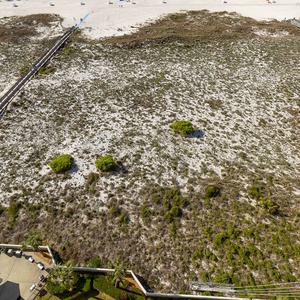 Wooden boardwalk paths invite you to stroll over dunes and soft coastal grass toward the beach coast