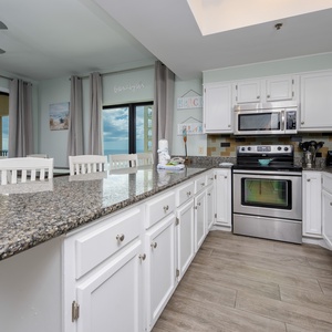 This kitchen features sleek stainless appliances, granite countertops, and a welcoming view of the beach from the dining area