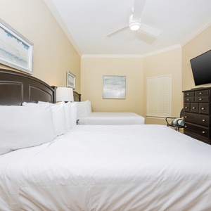This bedroom features two comfortable full beds, a mounted TV, and soft beige walls, creating a relaxing retreat