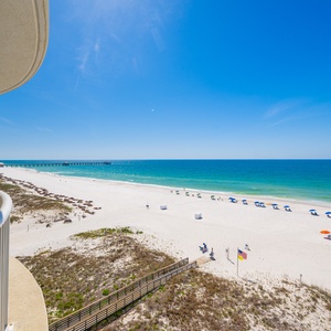 This serene beachfront view showcases soft white sands and gentle waves, perfect for a relaxing getaway