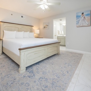 Stylish master bedroom featuring a king bed, elegant furnishings, and an ensuite bathroom visible in the background