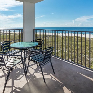 Balcony with a glass-top table and chairs offers a view of the beach and gulf, perfect for enjoying sunny days