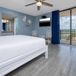 The master bedroom features a comfortable king bed, a wall-mounted TV, and a beautiful view from the balcony