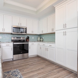 Prepare meals in this kitchen with elegant cabinetry, stainless appliances, and stylish backsplash
