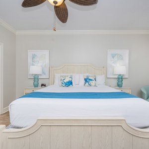 Retreat to the master suite featuring a king bed, coastal-themed decor, and a cozy reading nook for relaxation