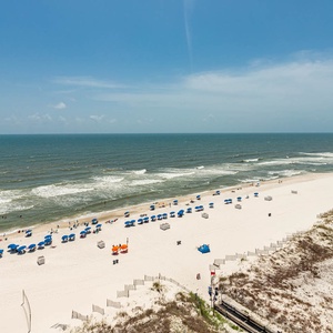 Enjoy the vibrant beach scene with colorful umbrellas and rolling waves under a clear blue sky