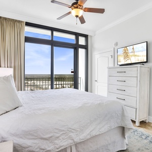 This bright bedroom features a cozy white king bed, a TV, and stunning views from large windows that invite relaxation