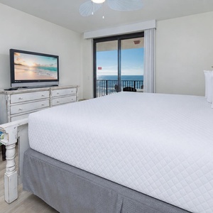 Relax in the comfortable master bedroom with a cozy chair, king bed, TV, and beautiful views through sliding glass doors