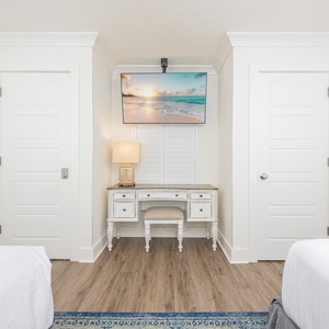Guest room featuring a stylish desk with comlementary WiFi, cozy seating, desk lamp, and a wall-mounted TV