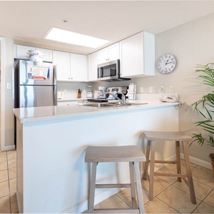Gather around the kitchen bar with two stools, featuring a sleek countertop and easy access to appliances for meal prep