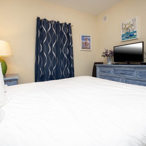 This bedroom features a comfortable bed, a TV for entertainment, and stylish blue decor, perfect for relaxation