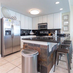 This kitchen features sleek stainless appliances, granite countertops, and a stylish bar area with seating for casual dining