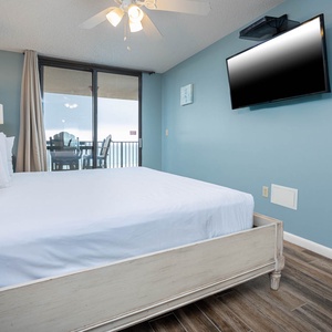 Relax in this tranquil master bedroom featuring a comfortable king bed, a large TV, and beachfront balcony access