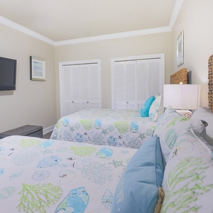 Rest in this cheerful guest bedroom with two queen beds, a TV, and coastal decor, creating a relaxing vibe for your stay