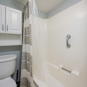 This bathroom features a clean design with a white shower curtain, modern cabinetry, and a convenient tub-shower combo