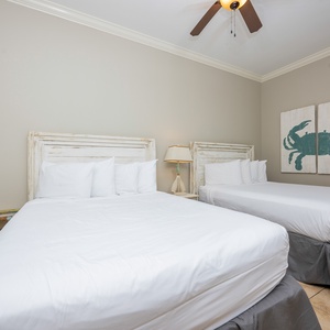 This guest bedroom features two comfortable full beds, coastal decor, and a charming artwork, perfect for a beach getaway