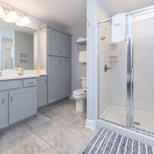 Enjoy a relaxing shower after a day at the beach in this guest bath with stylish accents and fluffy towels