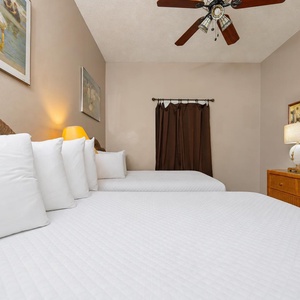 Rest in this inviting guest bedroom featuring two double beds, a TV, and warm lighting for a relaxing stay