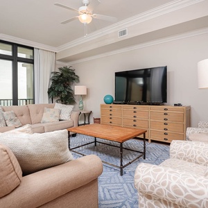 This inviting living area features a large TV, plush seating, and stunning views through expansive windows