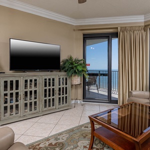 Cozy living area features a TV, sofa with queen sleeper, elegant coffee table, and access to a gulf front balcony