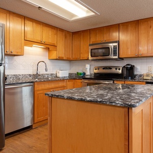 Warm wood cabinetry complements the granite countertops in this kitchen, featuring an island and wine cooler