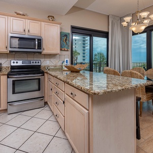 Modern kitchen with granite countertops, a breakfast bar, and stainless appliances offering views of the beach