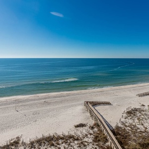 Stunning view of sparkling waters and sandy shores from a cozy balcony, perfect for relaxation and seaside enjoyment