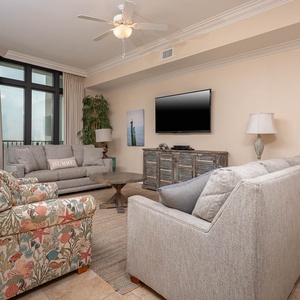 This inviting living area features colorful seating, a flat-screen TV, and large windows offering a serene state park view