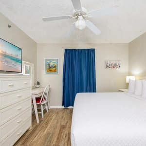 A king bed rests under ceiling fan breezes while you relax and watch your favorite show in the master suite