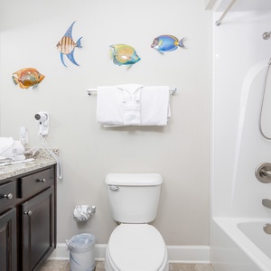 Enjoy a relaxing shower after a day at the beach in this guest bath with stylish accents and fluffy towels