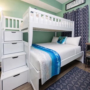 This colorful guest bedroom features a cozy bunk bed with storage drawers and a charming beach-themed decor for a fun stay