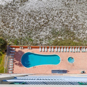 This view showcases a sparkling pool surrounded by lounge chairs and lush greenery, perfect for relaxation and fun