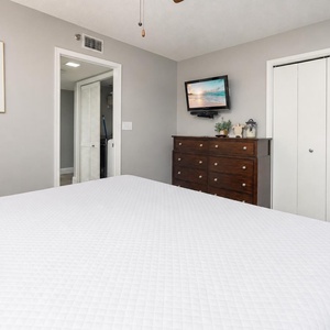 Brightly decorated guest room featuring a comfortable bed, dresser, TV, and a cozy chair in a welcoming atmosphere