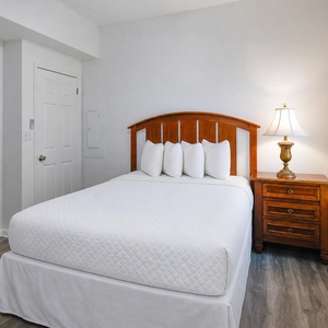 Cozy guest bedroom featuring a comfortable queen bed with plush pillows and warm accents, perfect for a restful getaway