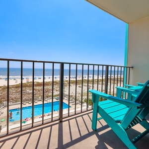 Enjoy relaxing beach views from this balcony, featuring comfortable seating and a glimpse of the pool below