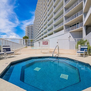 Relax in the inviting hot tub with a view of the vibrant pool area, perfect for unwinding after a day of fun