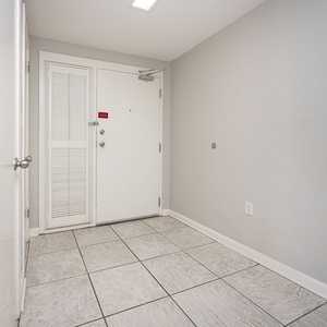 Welcoming entryway featuring tile flooring and a light gray wall, providing a clean and inviting atmosphere