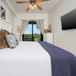 Inviting master bedroom featuring a king bed, decorative pillows, and a view of the lush greenery from the beachfront patio