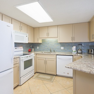 Prepare meals in this inviting kitchen, featuring granite countertops, white appliances, and a stylish backsplash