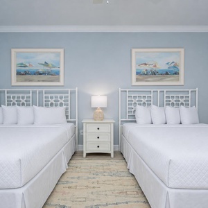 Rest in this inviting guest room featuring queen beds, gentle lighting, and a relaxing vibe