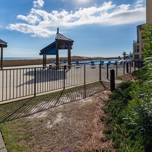 The pool area features shaded cabanas and lounge chairs, offering a relaxing spot with views of the beach beyond