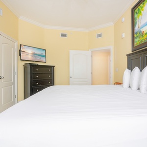 Guest bedroom featuring a cozy king bed, a mounted TV, and cheerful yellow walls for a calming retreat