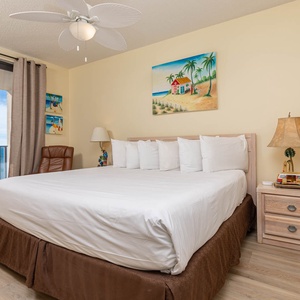 Unwind in the master bedroom featuring a large king bed, beach art, and access to the beachfront balcony