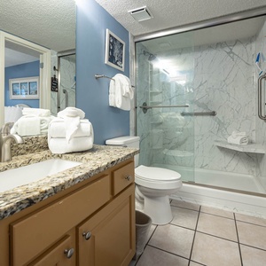 The bathroom features a granite countertop, walk-in shower, and neatly arranged towels for a refreshing experience