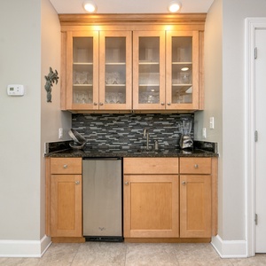Enjoy preparing drinks at the stylish wet bar, featuring a stylish glassware display and stainless ice maker