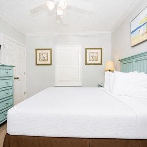 Rest in this serene guest bedroom featuring a large queen bed, a TV, and charming decor for a restful getaway