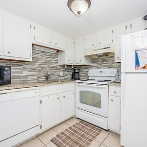The kitchen features white cabinets, granite countertops, and white appliances, perfect for preparing meals during your stay